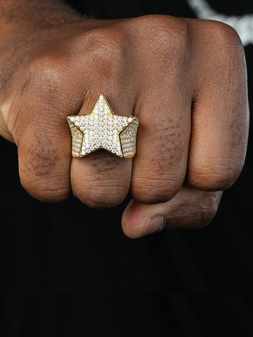 Star-shaped ring with diamonds on a person's finger against a black background